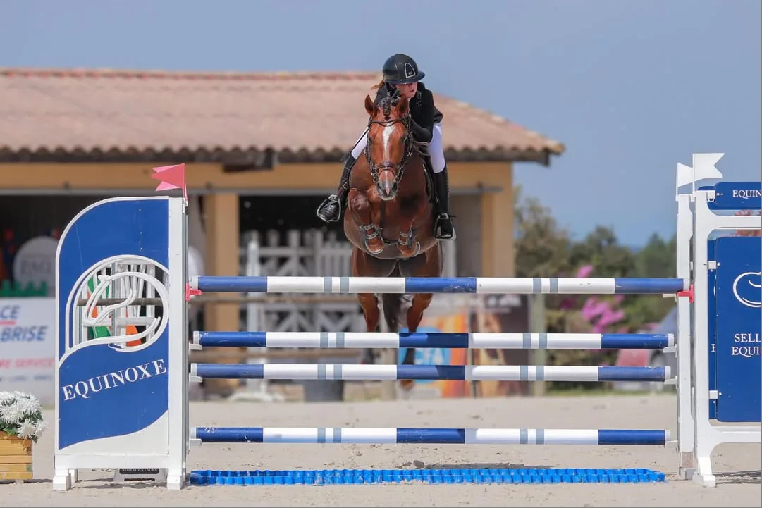 Cavalière et poney franchissant un obstacle en compétition