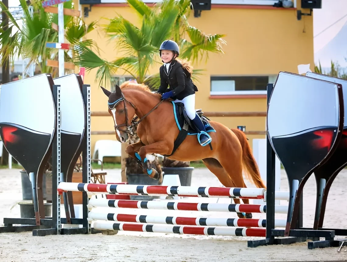 Jeune cavalière sur son poney franchissant un obstacle en concours